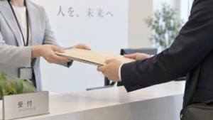 会社の担当者から退職関係の書類が入った封筒を受け取る様子